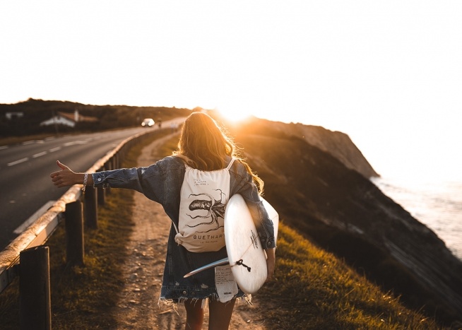  - Naturposter mit einer Surferin, die mit ihrem Surfboard unterm Arm dem Sonnenuntergang entgegentrampen möchte.