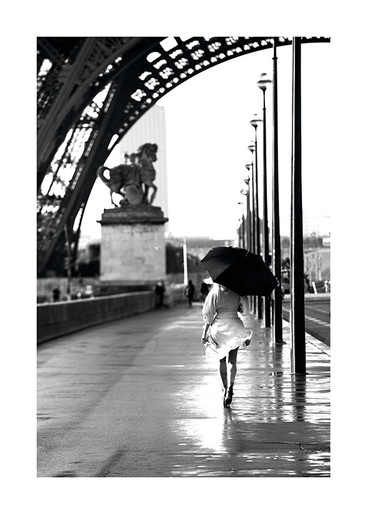  – Schwarz-weiß-Fotografie mit einer Frau, die mit einem Regenschirm unterhalb des Eiffelturms spazieren geht