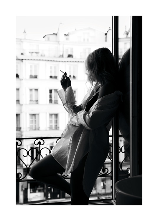  – Schwarz-weiß-Fotografie von einer Frau, die ein zu großes Hemd trägt und eine Zigarette in einem Fenster raucht
