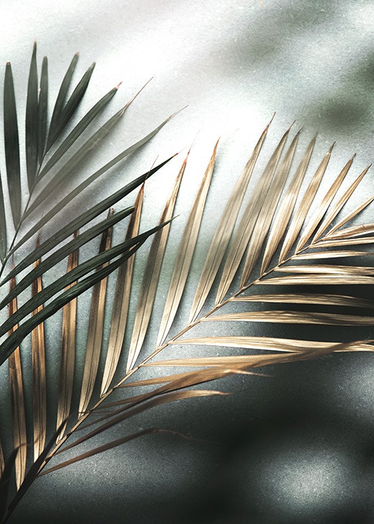  – Fotografie mit einem Paar Palmblättern in Gold und Grün vor einem Steinhintergrund
