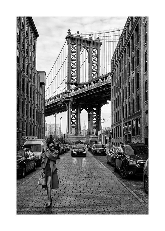  – Schwarz-weiß-Fotografie einer Frau, die auf einer Straße in New York vor der Manhattan Bridge steht