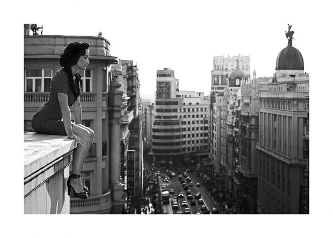 Schwarz-weiß-Fotografie von einer Frau, die vom Dach aus auf die Stadt schaut