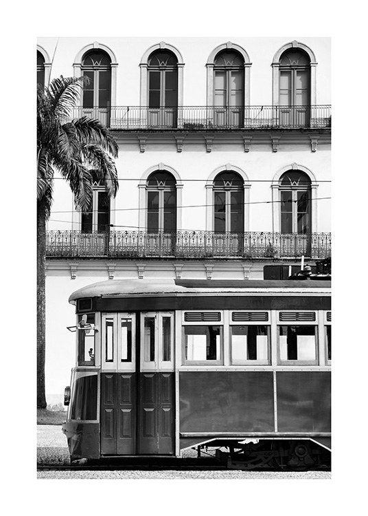  - Schwarz-weiß-Fotografie von einer alten Straßenbahn, dahinter ein Gebäude mit Balkonen und einer Palme