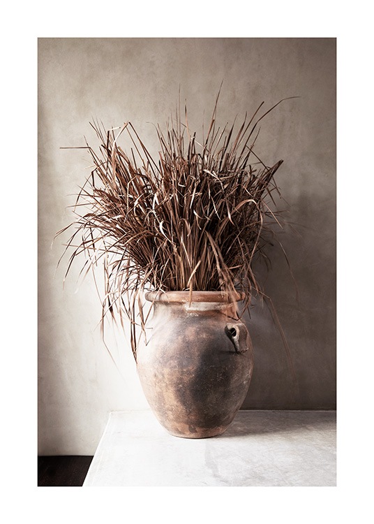  – Fotografie von getrocknetem, beigem Gras in einer Vase vor einer Betonwand in Beige