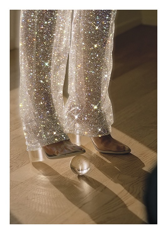  – Fotografie einer Frau mit einer Glaskugel unter der Ferse, die funkelnde Hosen trägt