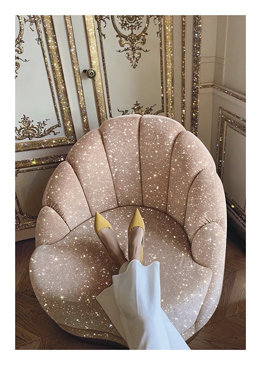  – Foto eines glitzernden rosa Stuhls vor einer gold-weißen Wand mit einer Frau, die die Füße auf den Stuhl gelegt hat