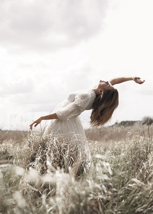  – Fotografie einer Frau, die in einem weißen Kleid vor hohem Gras posiert