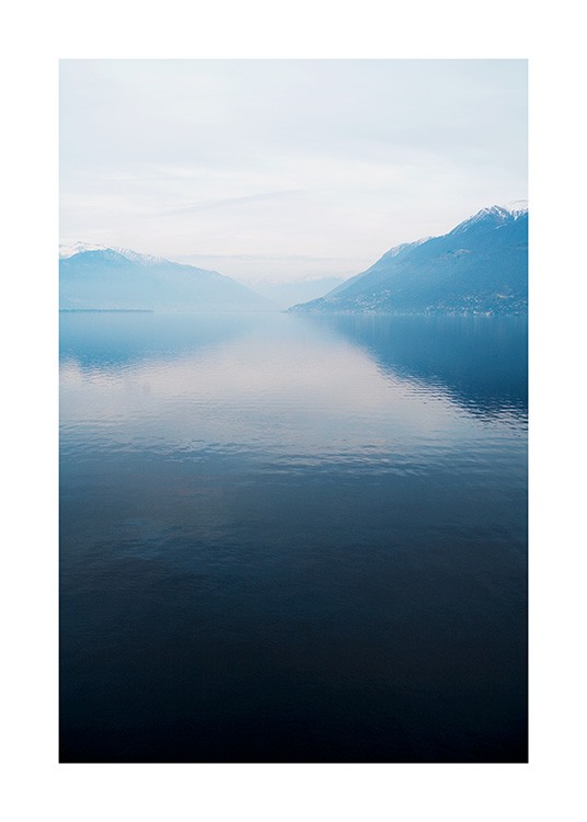  – Fotografie eines Sees mit einer stillen Oberfläche, im Hintergrund Berge und Nebel