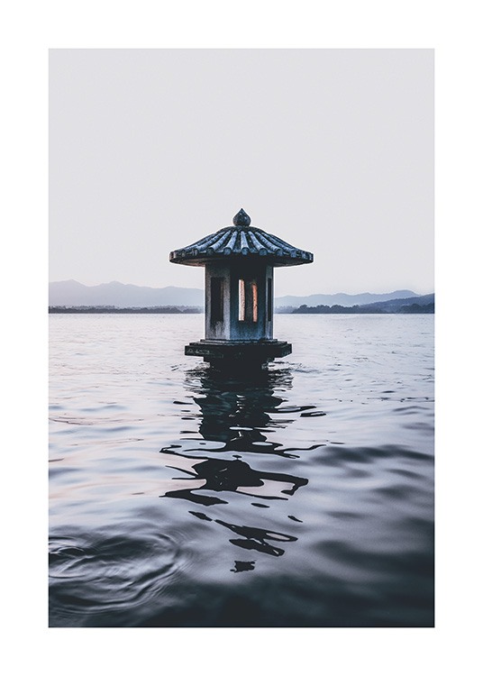  – Fotografie, die einen See mit einem kleinen Leuchtturm zeigt, im Hintergrund Berge