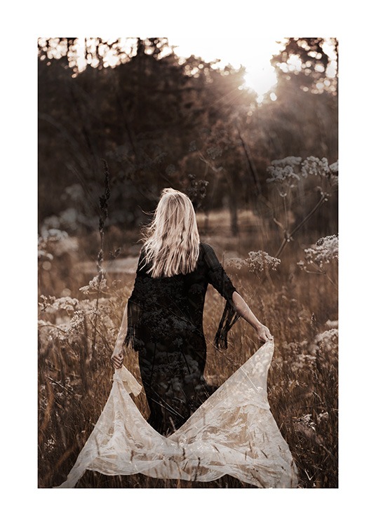  – Fotografie einer Frau, die in einem schwarzen Kleid durch ein Feld geht und eine weiße Spitze hinter sich herzieht