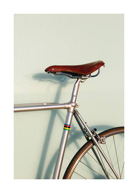  – Fotografie eines Fahrrads in Grau mit einem braunen Sattel und einem grünen Hintergrund dahinter
