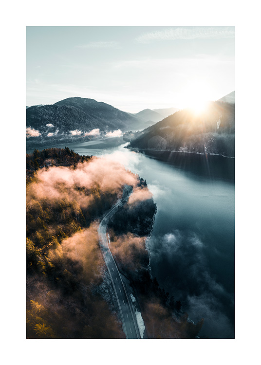  – Fotografie einer Landschaft mit einer Straße zwischen Wald und See, im Hintergrund Berge und die Sonne