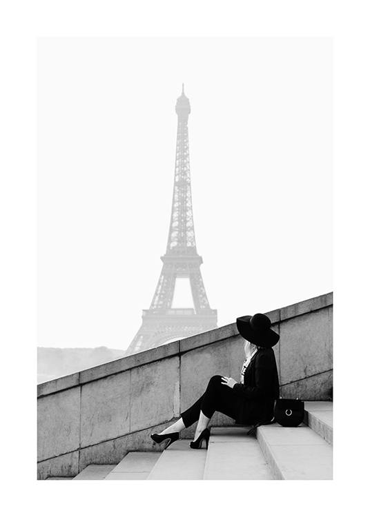  – Schwarz-weiß-Fotografie einer Frau, die auf einer Treppe sitzt, im Hintergrund der Eiffelturm
