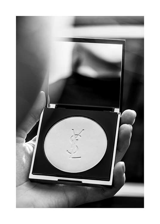  – Schwarz-weiß-Fotografie von einer Hand, die YSL-Puder mit einem Spiegel in der Hand hält