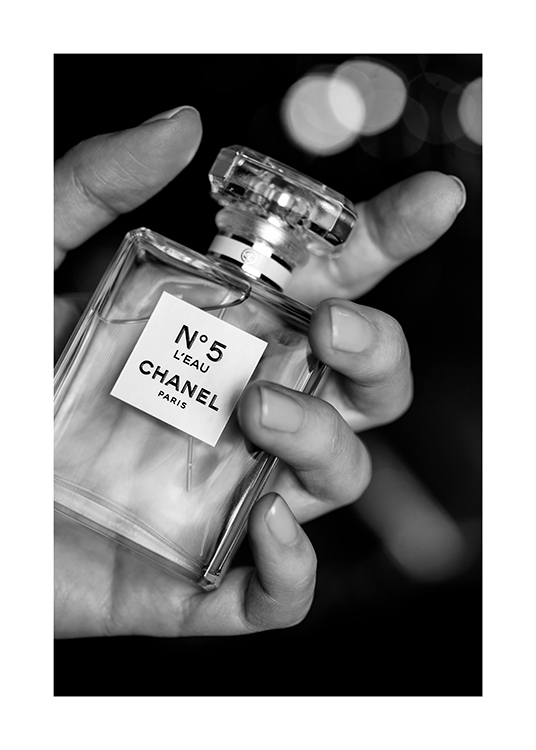  – Schwarz-weiß-Fotografie, die einen Flakon mit dem Parfüm Chanel No5 in einer Hand zeigt