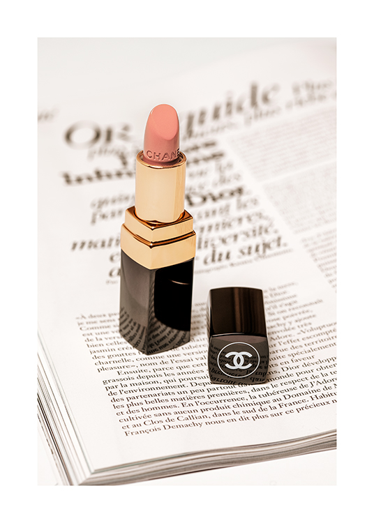  – Fotografie eines Chanel-Lippenstifts in Hellrosa mit einer Buchseite darunter