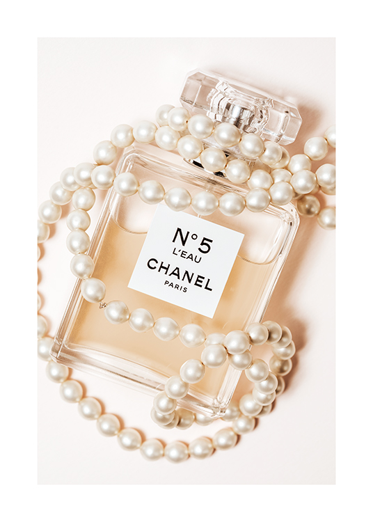  – Fotografie einer Parfümflasche mit der Inschrift Chanel No5, umgeben von einer weißen Perlenkette