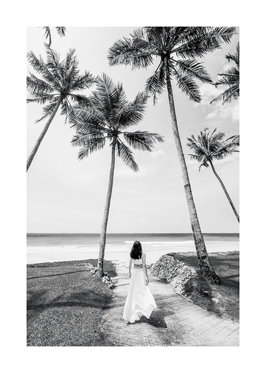  – Schwarz-weiß-Fotografie einer Frau, die in einem langen Kleid zwischen Palmen steht