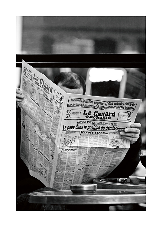  – Schwarz-weiß-Fotografie eines Mannes, der eine Zeitung namens Le Canard enchainé liest