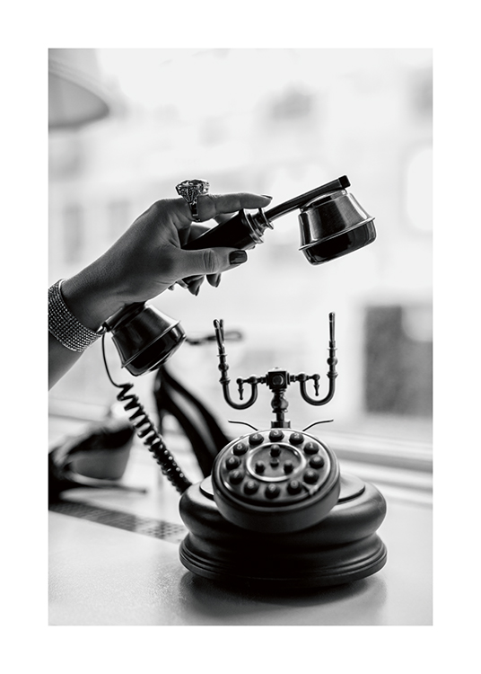  – Schwarz-weiß-Fotografie von einer Frau, die einen altmodischen Telefonhörer abnimmt und einen Statement-Ring trägt