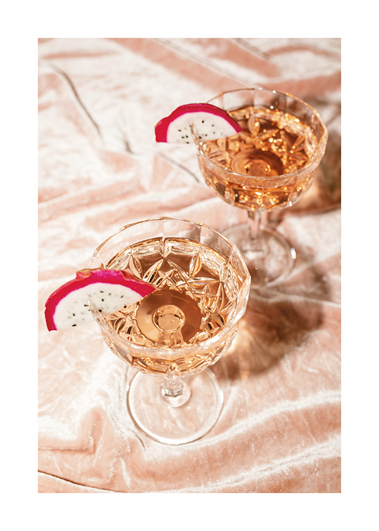  – Fotografie mit zwei perlenden Rosé-Cocktails in Kristallgläsern mit Drachenfruchtscheiben