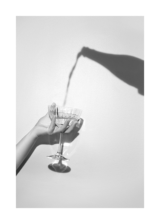  – Graues Foto mit dem Schatten einer Champagnerflasche und einer Hand, die ein Champagnerglas hält