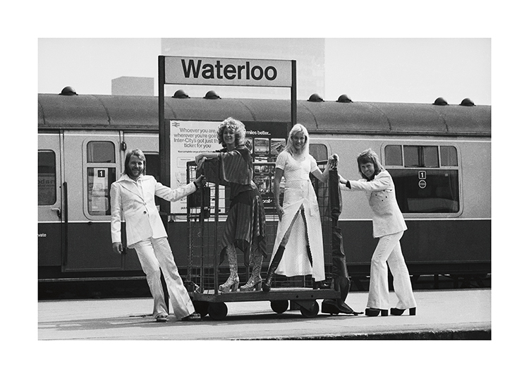  – Fotografie in Schwarz-Weiß der Musikgruppe ABBA, die am Bahnhof Waterloo Station steht
