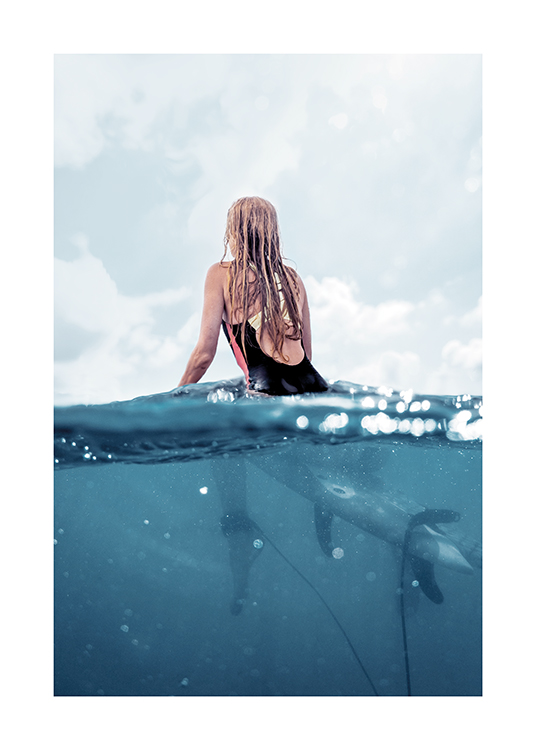  – Fotografie einer Frau in Rückenansicht, die auf einem Surfbrett im Meer sitzt