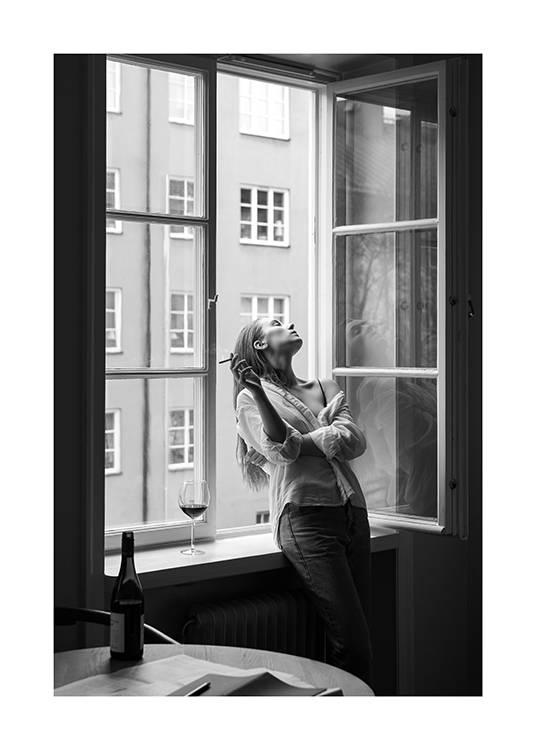  – Schwarz-weiß-Fotografie einer Frau, die eine Zigarette hält und sich rückwärts aus einem offenen Fenster lehnt
