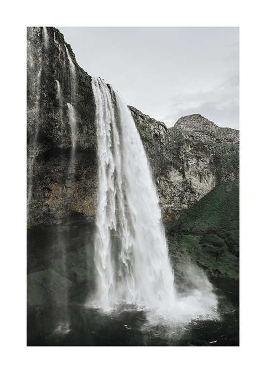  – Fotografie eines Wasserfalls in einer Klippenlandschaft mit grüner Vegetation im Hintergrund