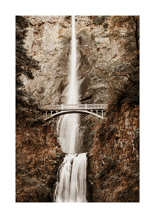  – Fotografie eines Wasserfalls in den Bergen mit einer Brücke in der Bildmitte