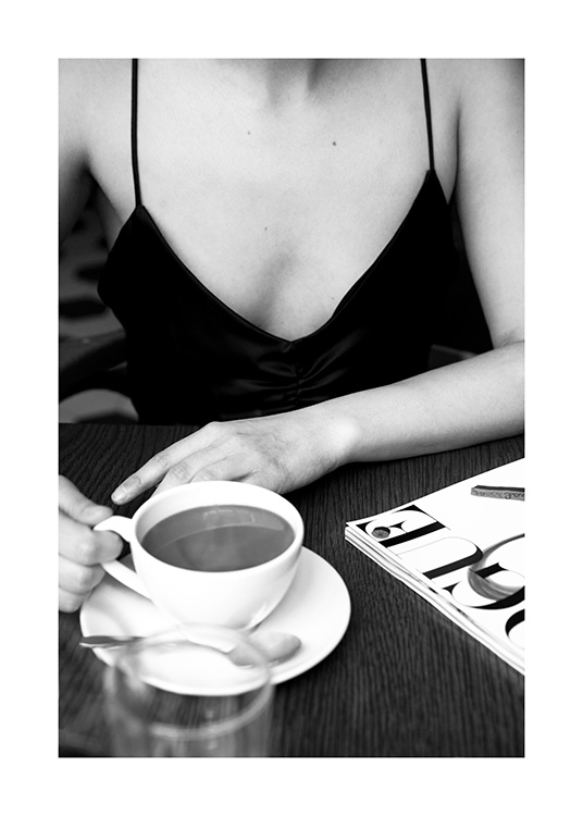  – Schwarz-Weiß-Fotografie einer Frau, die mit einer Tasse Kaffee auf dem Tisch in einem Café sitzt