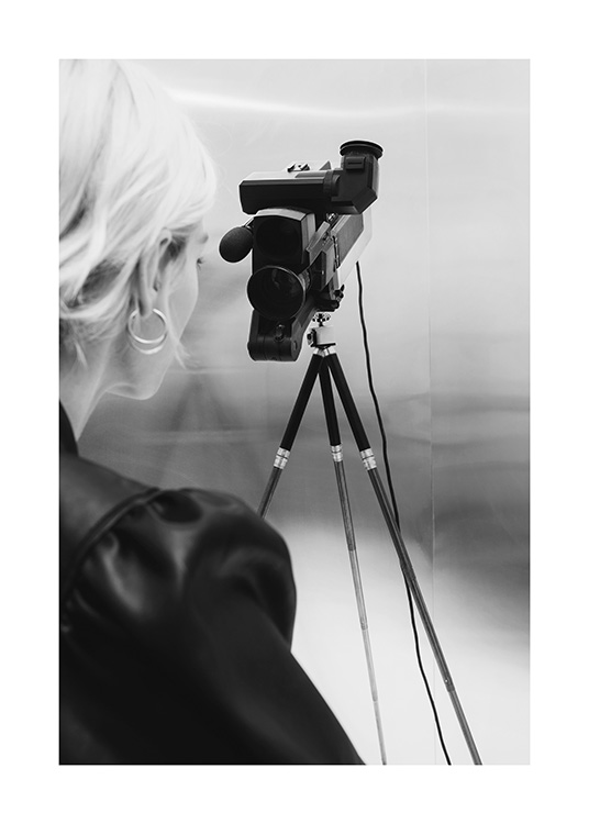  – Schwarz-Weiß-Fotografie einer blonden Frau, die hinter einer Videokamera steht