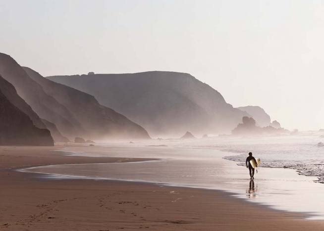 - Tolle Fotokunst mit einem Surfer samt Surfboard unter dem Arm an einsamen Bucht.