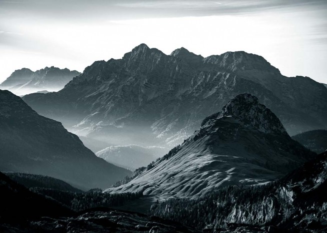  - Schwarzweißes Naturfoto einer alpinen Gebirgskette, die teilweise mit Schnee bedeckt ist.